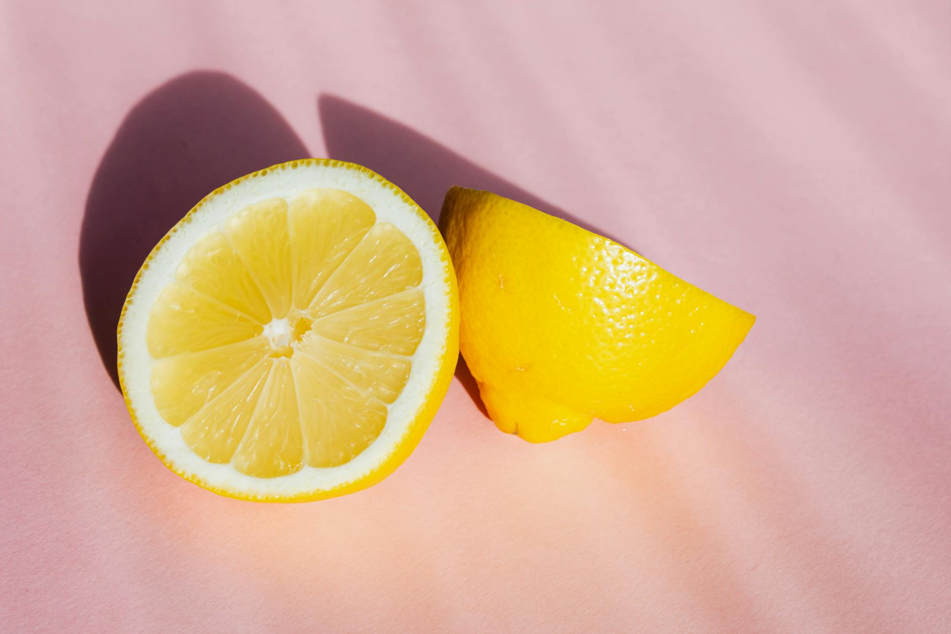 Bright halves of fresh lemon on a pink background in sunlight
