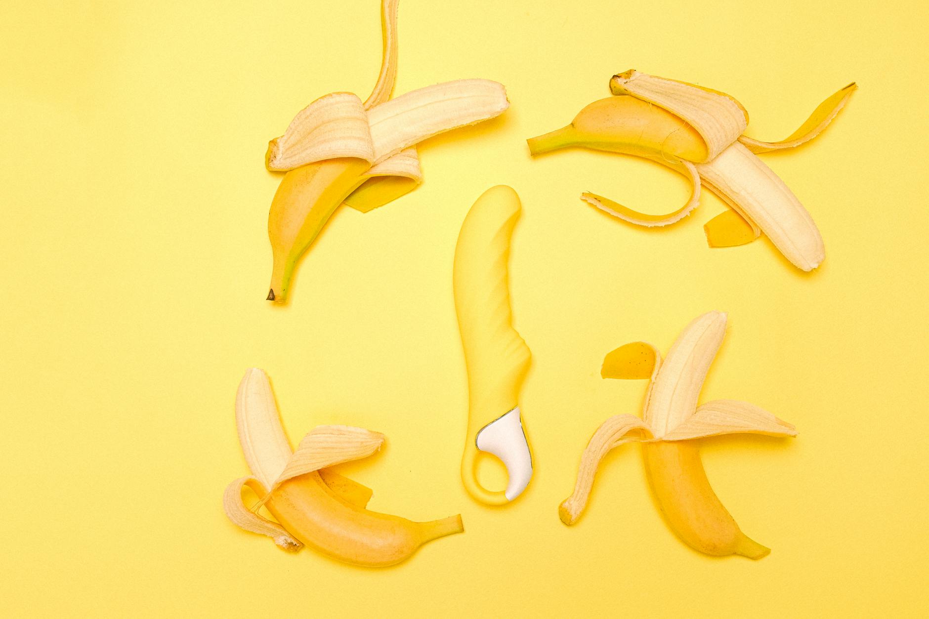 Gelber Lemon-Vibrator umgeben von geschälten Zitronen auf gelbem Hintergrund