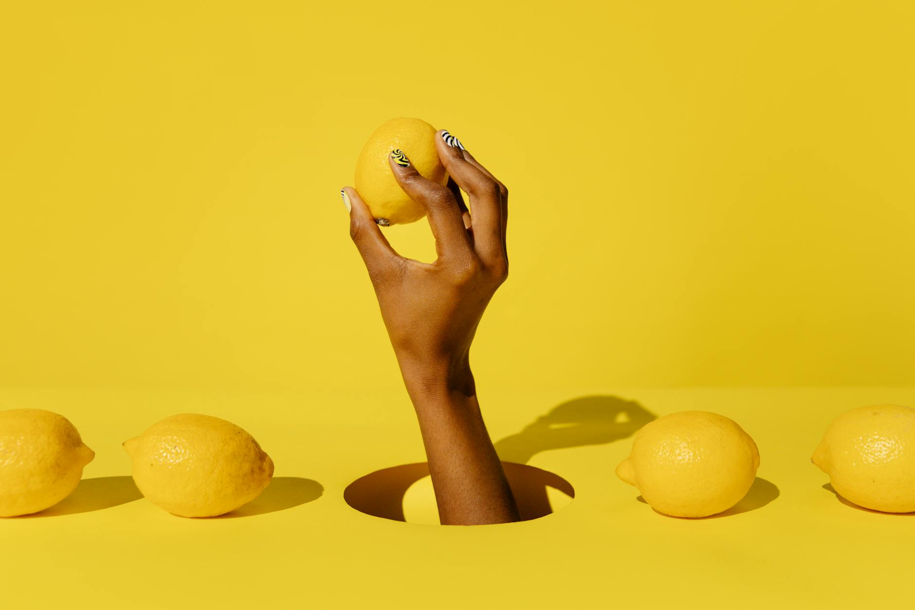 Hand hält frische Zitrone vor leuchtend gelbem Hintergrund, symbolisiert Frische und Neubeginn nach hormonellen Veränderungen