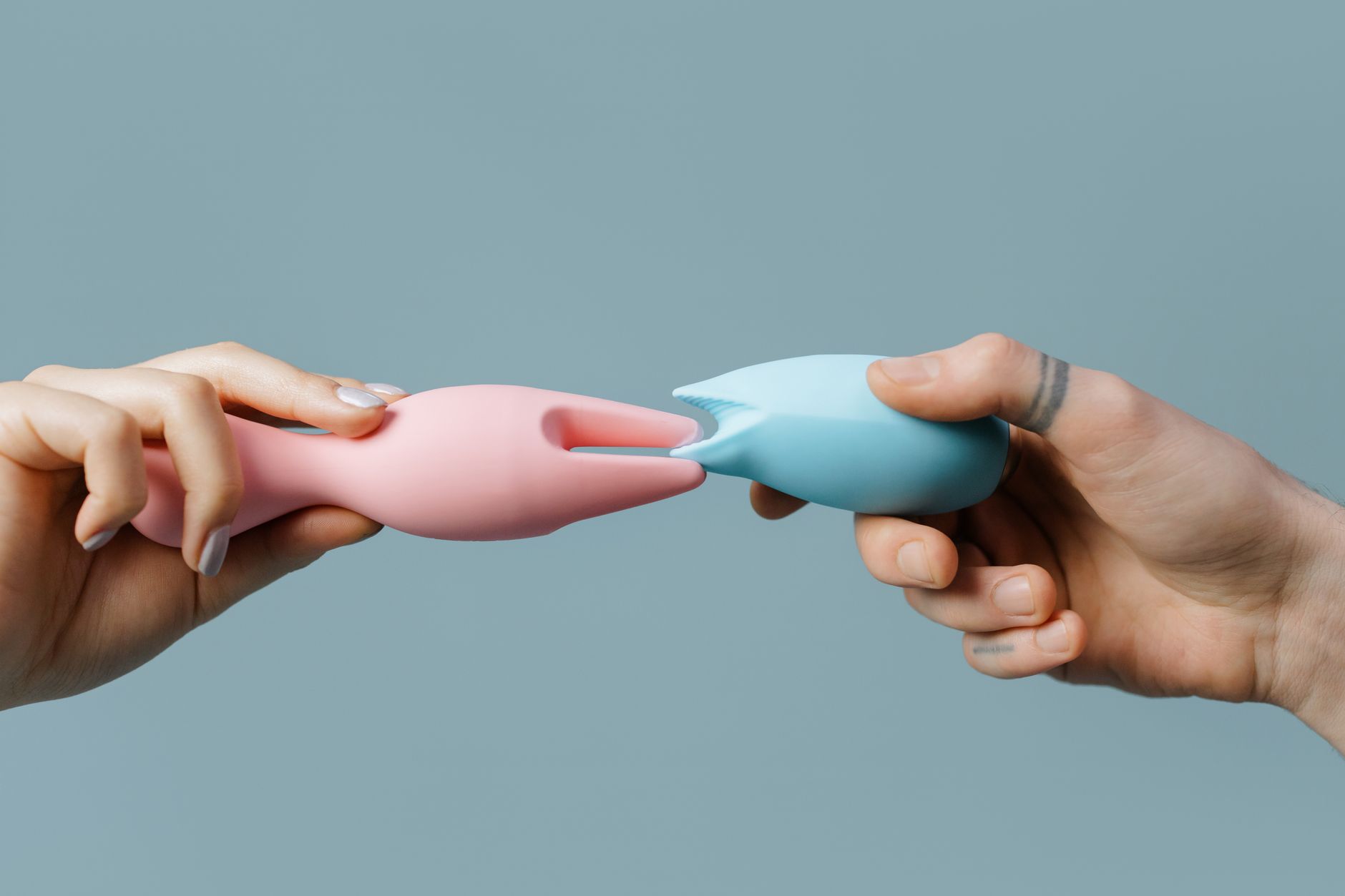 Hands holding pastel-colored silicone toys, demonstrating accessible grip and positioning options