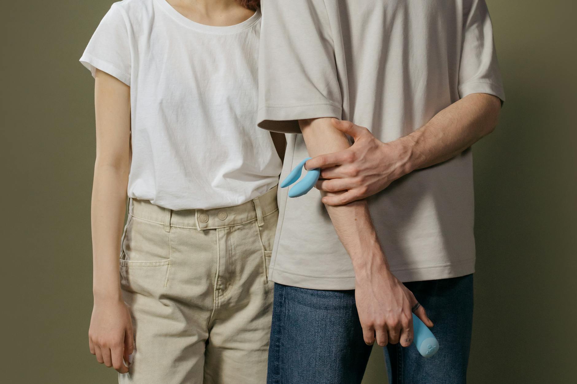 A couple holding hands on a bed, representing intimate reconnection after birth.