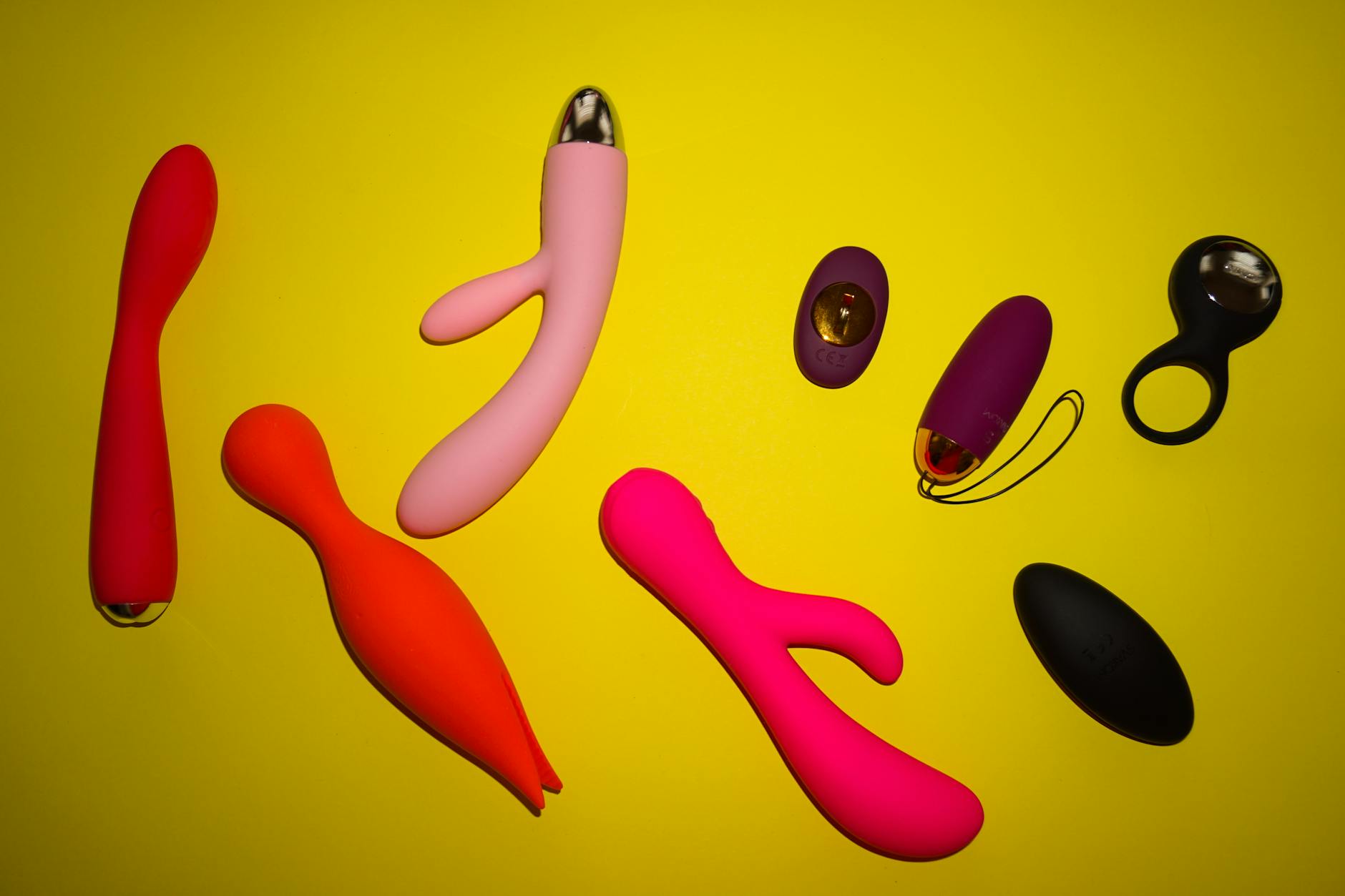 Bunte Lemon-Vibratoren und andere Sextoys nebeneinander auf gelbem Hintergrund